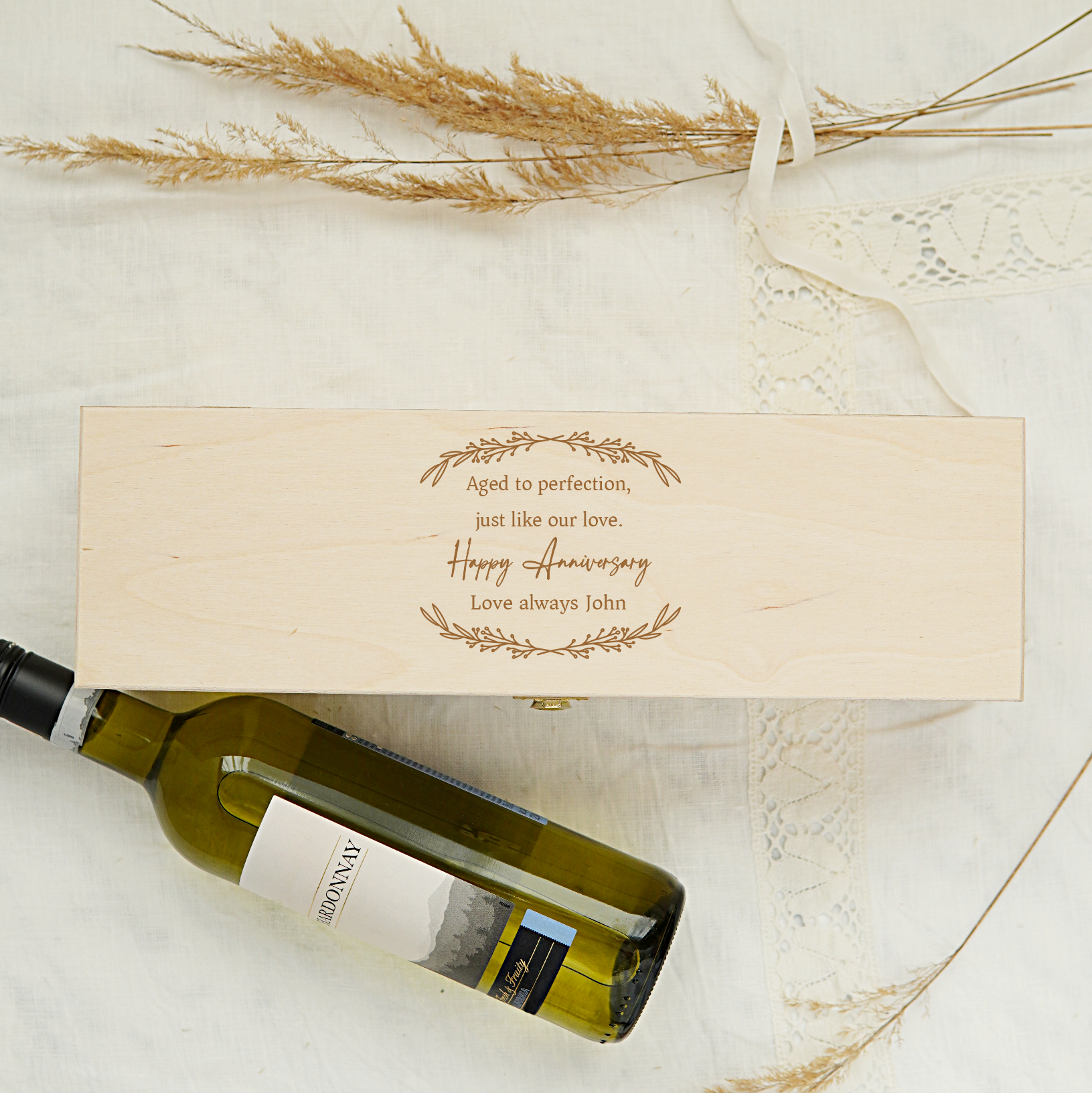 Wine bottle with wooden box and decorative text on a light background