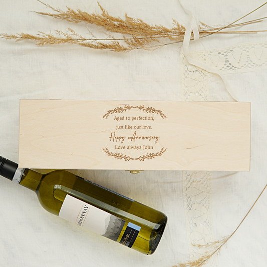 Wine bottle with wooden box and decorative text on a light background